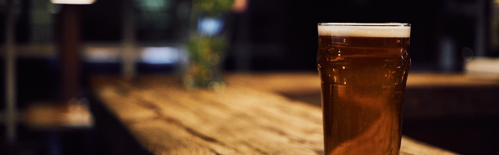 A pint of beer sitting on a bar.