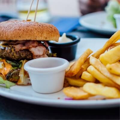 A bacon cheeseburger with fries and condiment ramekins.